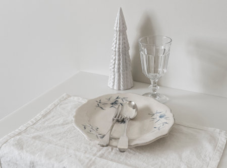 Christmas table setting - vintage plate, silver cutlery, glass and Christmas decor on a white tableの写真素材