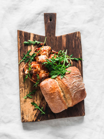Roasted meatballs with tomato sauce and mozzarella cheese ciabatta burger on a wooden chopping board on a light background, top viewの写真素材