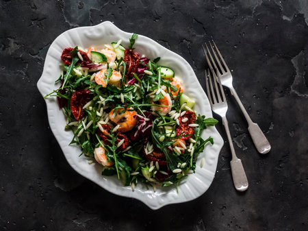 Arugula salad with shrimp, avocado, cucumber and risoni pasta on a dark background, top viewの写真素材
