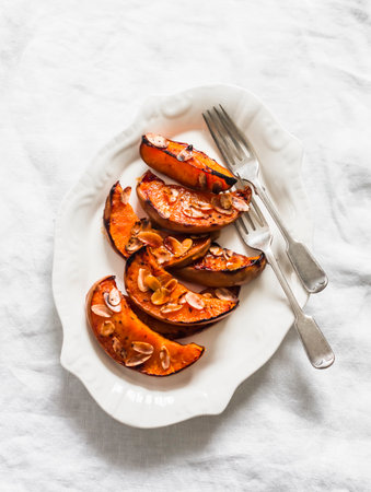 Delicious appetizer, tapas, dessert, snack - baked pumpkin with honey, cinnamon and almond petals on a light background, top viewの写真素材