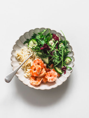 Delicious lunch - risoni pasta, shrimp and arugula, cucumber, celery salad on a light background, top viewの写真素材