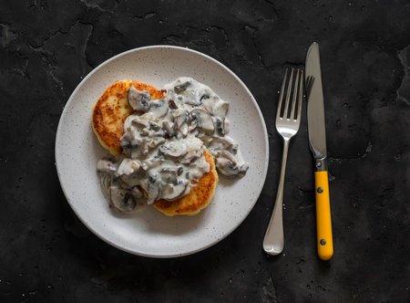 Vegetarian potato patties with creamy mushroom sauce on a dark background, top viewの写真素材