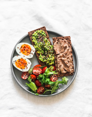 Delicious breakfast, tapas, snack - crispy rye bread crackers with turkey liver, avocado, boiled egg...
