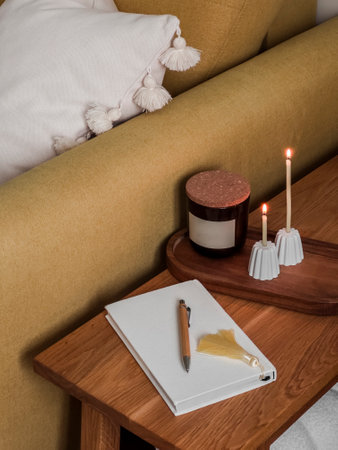 A cozy corner of the living room - a diary, candles on a wooden bench next to an armchairの写真素材