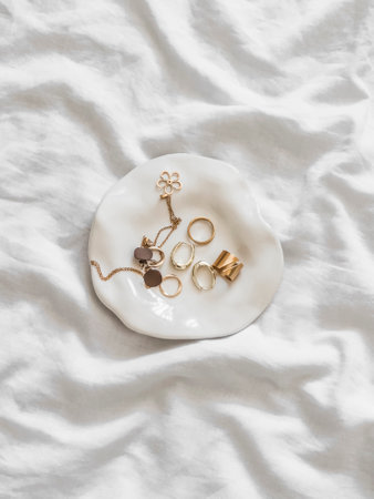 Women's gold jewelry, jewelry - rings, earrings, chains on a white retro plate on a light...