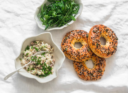Ingredients for making breakfast, brunch, snack - tuna eggs salad, arugula and bagels on a light background, top viewの写真素材