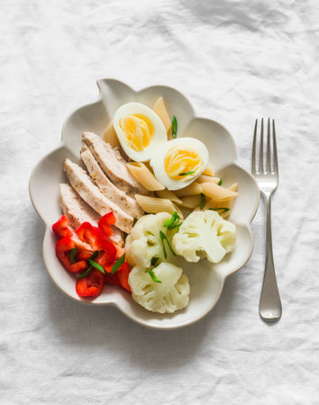 Healthy lunch - baked chicken breast, egg, fresh sweet pepper and boiled cauliflower on a light background, top viewの写真素材