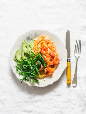 Delicious breakfast, brunch - omelette with shrimp, arugula and avocado on a light background, top viewの写真素材