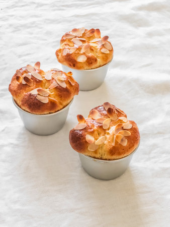 Fresh pastries - brioche buns with almond petals in a baking dish on a light background, top viewの写真素材