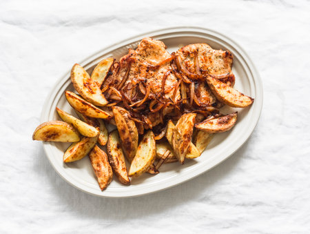 Delicious lunch, dinner - pork chop, baked new potatoes and caramelized onions in one plate on a...