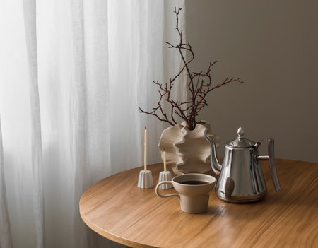 Coffee break. A cup of coffee, a metal coffee pot, decor, candles on a round wooden table in the living roomの写真素材