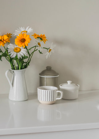 Kitchen still life - dishes, a bouquet of daisies in a jug on the kitchen table. Minimalism style...
