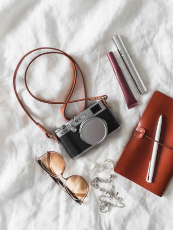 Aesthetic details, women's accessories - retro camera, leather notebook, sunglasses, cosmetics on a light background, top viewの写真素材