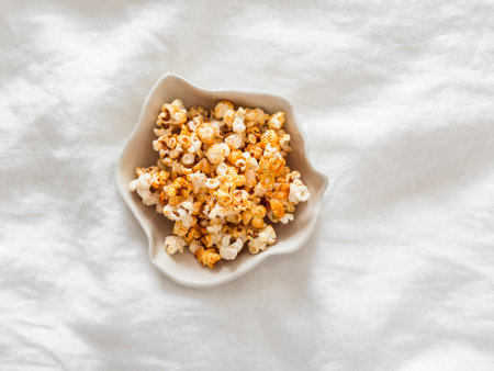 Caramel crunchy popcorn in a ceramic bowl on a light background, top viewの写真素材