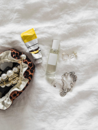 Aesthetic women's accessories - cosmetic bag, perfume, jewelry, hand cream on a light surface, top viewの写真素材