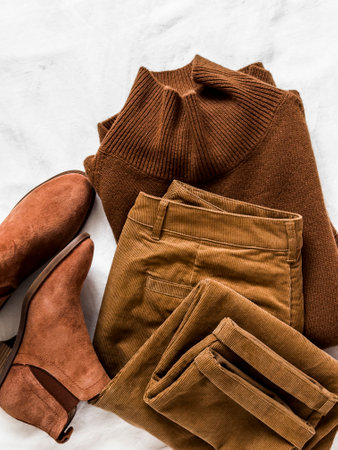 Women's clothing - brown corduroy trousers, cashmere pullover and suede chelsea boots on a light surface, top viewの写真素材