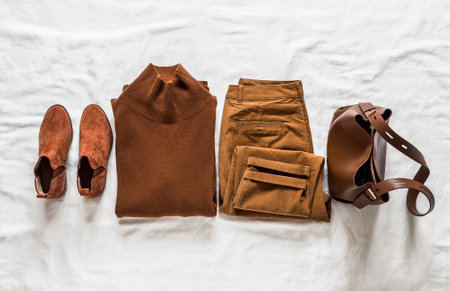 Women's casual clothing autumn winter spring season - corduroy jeans, cashmere sweater, chelsea boots, leather bag on a light surface top viewの写真素材