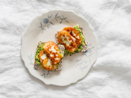 Whole grain crispbread with avocado and fried halloumi cheese on a light background, top viewの写真素材