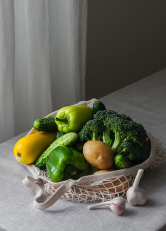 Eco string bag with fresh seasonal garden vegetables from the market on the tableの写真素材