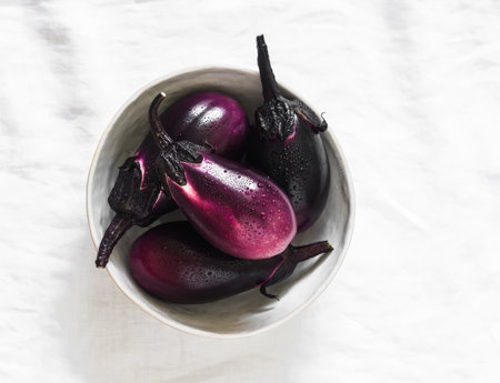 Fresh ripe eggplant in a ceramic bowl on a light backgroundの写真素材