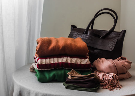 Seasonal shopping - a stack of cozy sweaters, cardigans, cotton socks, a cashmere scarf and a brown...