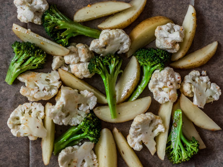 Lunch preparation - raw vegetables cauliflower, potatoes, broccoli with spices and olive oil on a baking sheetの写真素材