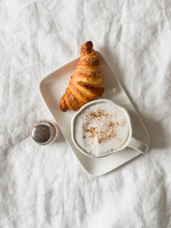 Cappuccino with cinnamon and fresh crispy croissant - lazy morning, breakfast in bedの写真素材