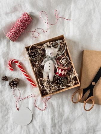 A Christmas present. Craft box, scissors, Christmas decorations, ribbon, candy on a light background, top viewの写真素材