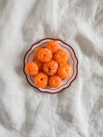Peeled tangerines on a plate on a light background, top viewの写真素材