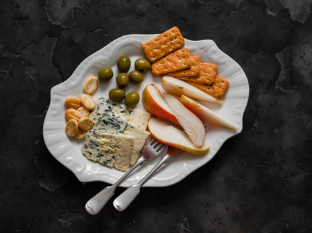 Delicious appetizer, tapas - cracker, olives, gorgonzolla, pear on a dark background, top viewの写真素材