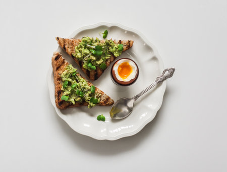 Delicious breakfast, snack, brunch - boiled egg and avocado whole grain bread on a light background, top viewの写真素材