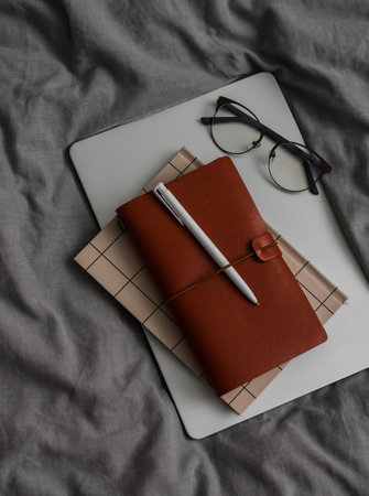 Notebook, glasses on a gray textile background, top view