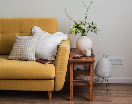 Cozy home - yellow sofa, wooden bench with a vase of fresh flowers, paper lamp in the living room interiorの写真素材