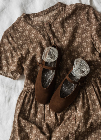 Retro style women's summer clothes - brown muslin dress, suede sandals, nylon socks on a light...