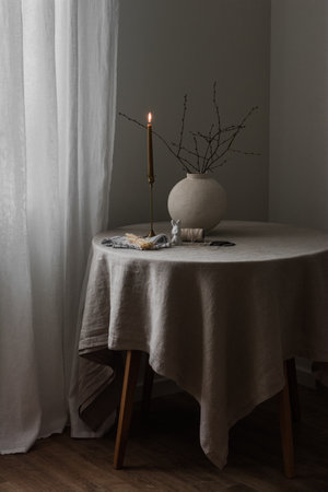Easter mood in the house - ceramic vase, candles, Easter decor on the round table in the living roomの写真素材