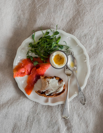 Delicious breakfast, brunch, snack - boiled egg, salmon, arugula, bun sandwich on a gray background, top viewの写真素材