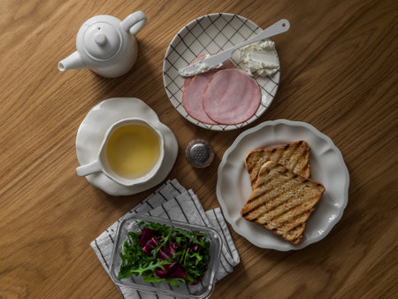 Breakfast and snack ingredients - ham, cheese, green salad, toast, on a wooden table, top viewの写真素材