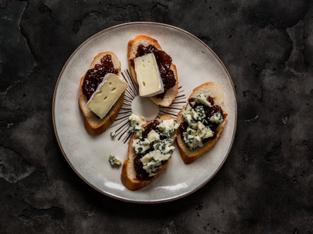 Bruschetta with fig jam and camembert, gorgonzola cheese on a dark background, top viewの写真素材