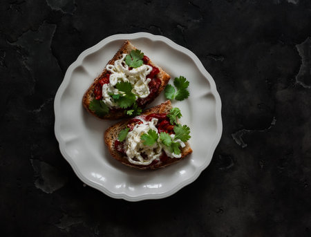 Delicious sandwich with baked peppers, strachatella and cilantro - delicious appetizer, tapas, snack on a dark background, top viewの写真素材