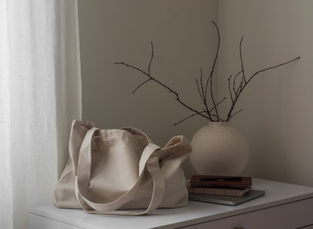 Women's textile shopping bag, notebooks, laptop and ceramic vase on a white table in the living roomの写真素材