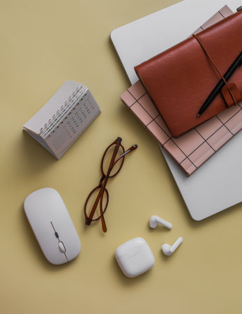 Laptop, notepad, wireless headphones, calendar on a yellow background, top view. Business, training conceptの写真素材