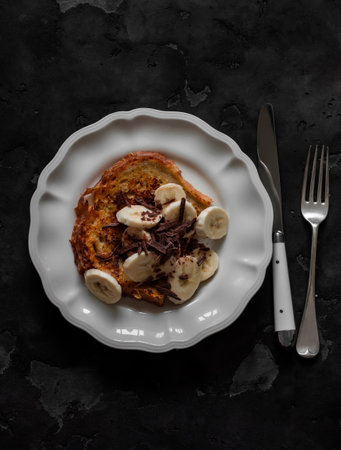 French toast with banana and chocolate chips - delicious breakfast, dessert, snack on a dark background, top viewの写真素材