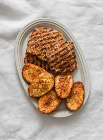 Pork chops, grilled turkeys and baked potatoes - delicious lunch, dinner on a light background, top viewの写真素材