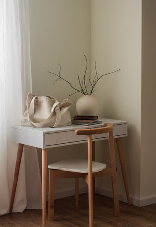 A shopping bag, a laptop, a notebook, a vase with branches on a white table in the living room. Cozy...