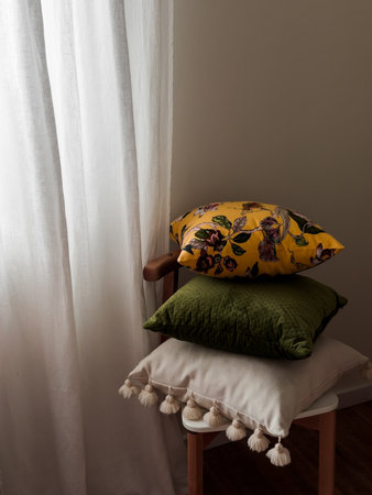 A stack of decorative pillows on a chair in the bedroom. Cozy interior conceptの写真素材