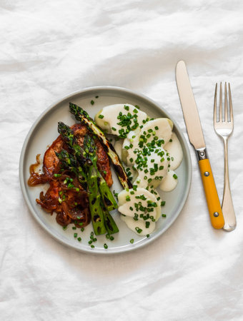 Delicious lunch and dinner - pork chop, asparagus, potatoes with yogurt sauce on a light background, top viewの写真素材