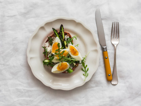 Sandwich with cottage cheese, grilled asparagus, boiled egg - delicious breakfast, snack, tapas on a light background, top viewの写真素材