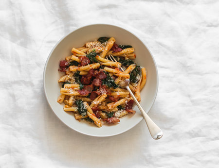 Quick pasta recipe - casarecce with spinach and bacon on a light background, top viewの写真素材