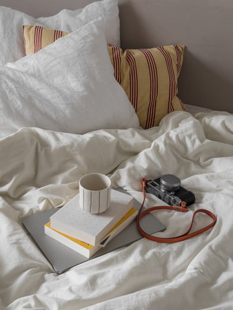 Slow morning in bed - laptop, books, camera, a glass of coffee on the bedの写真素材