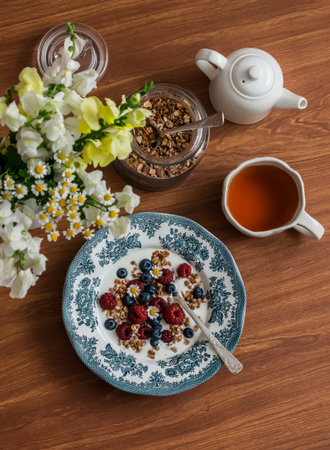 Breakfast served on the table - Greek yogurt, granola, fresh berries and tea, top viewの写真素材